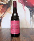 Wine bottle labelled 'Robbing Red Breast 2024' on a wooden surface with an artistic wine glass background