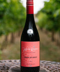 A bottle of Wressle Vineyard Robbing Red Breast 2024 red wine stands on a metal patio table with a blurred vineyard background.