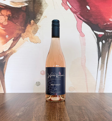 Bottle of Holy Moley 2025 Pinot Noir rosé from Wressle Vineyard, North Lincolnshire, with a dark navy label, standing on a wooden table