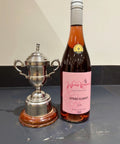 Bottle of Wressle Vineyard Otters Plunder 2024 rose wine next to a silver trophy on a marble worktop.