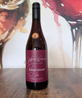 Wine bottle labelled 'Plucked Pheasant 2024' on a wooden surface with a colourful abstract background