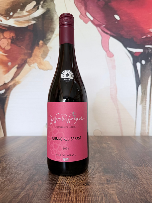 Wine bottle labelled 'Robbing Red Breast 2024' on a wooden surface with an artistic wine glass background