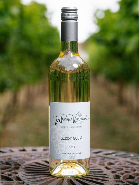 A bottle of Wressle Vineyard Giddy Goose 2025 white wine stands on a metal patio table with a blurred vineyard background.