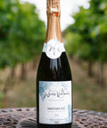 A bottle of Wressle Vineyard Kingfisher Kiss 2024 sparkling white wine, set on a decorative metal table with a blurred vineyard background.