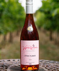 A bottle of Wressle Vineyard Otters Plunder 2024 rose wine stands on a metal patio table with a blurred vineyard background.