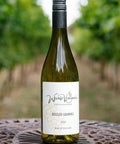 A bottle of Wressle Vineyard Sozzled Squirrel 2023 wine stands on a decorative metal table with a blurred vineyard background.