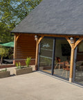 Outdoor seating area with oak framed building and tables under green umbrellas
